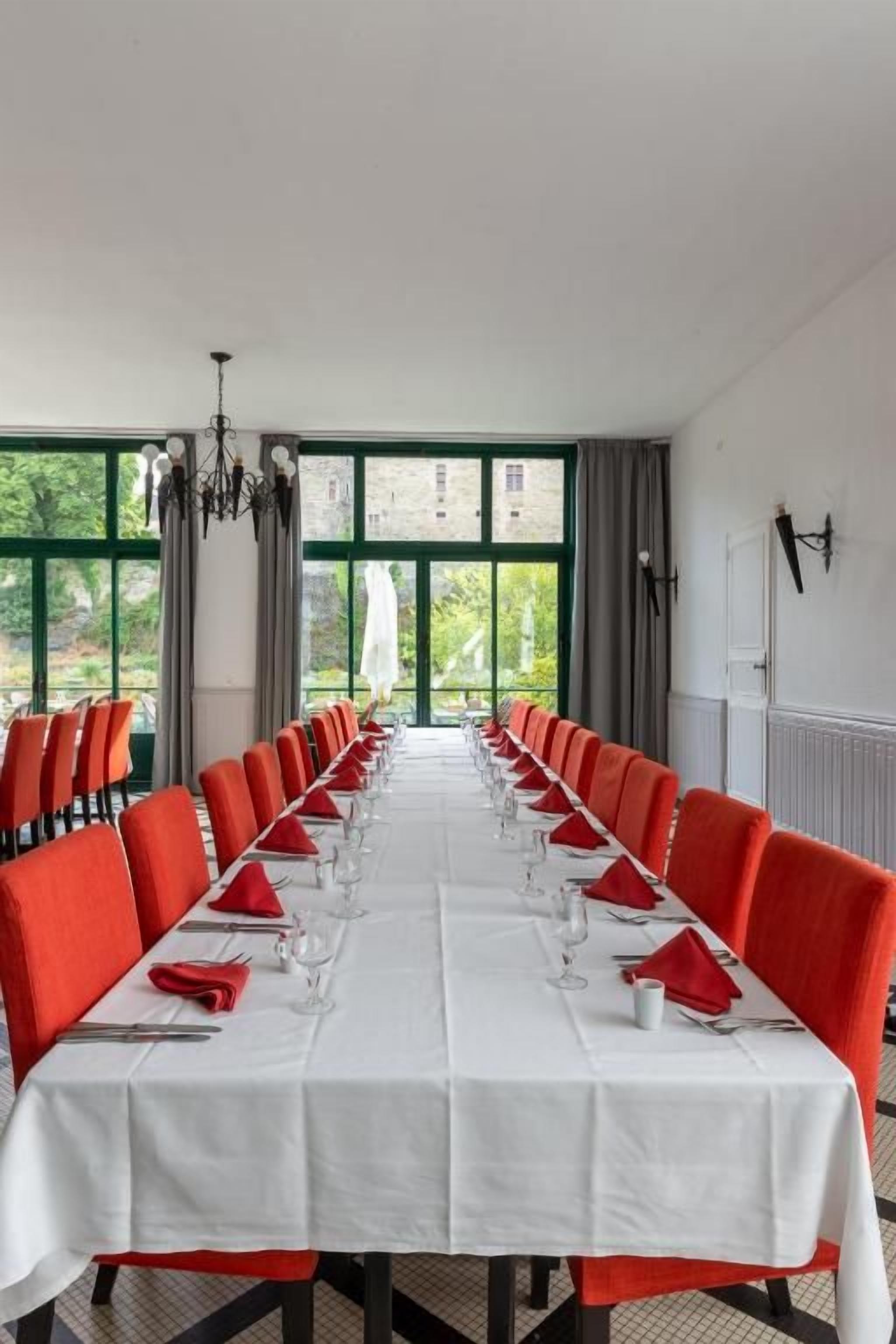 A conference room with a long table, red chairs, and a view through large windows.