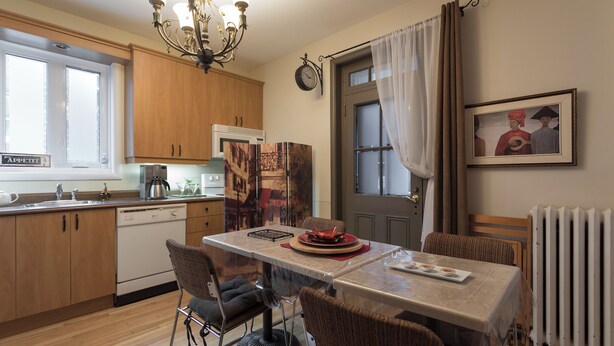 A modern kitchen with wooden cabinets, a dishwasher, and a dining table set for two.