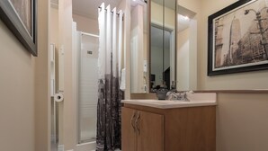 A bathroom with a wooden cabinet, a mirror, and a framed picture on the wall.
