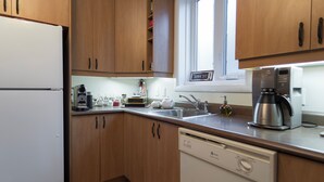 A kitchen with wooden cabinets, a white refrigerator, a coffee maker, and a dishwasher.