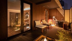 A modern interior with a wooden deck, a hot tub, and a seating area with cushions.