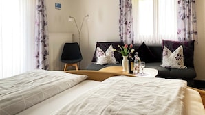 Een hotelkamer met twee bedden, een bank, een kleine tafel met een bloemenvaas en een stoel.