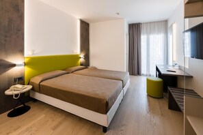 A hotel room with a bed, bedside table, lamp, and a desk with a chair. - Hotel Italy (San Michele al Tagliamento)