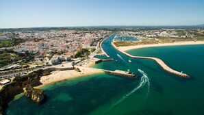 An aerial view of a coastal city with a prominent beach, a marina, and a fortified structure. - C05 - Convento Apartment (Lagos)