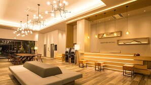 A modern hotel lobby with a reception desk, seating area, and a dining space. - Airport Hotel Kumamoto (Ozu)