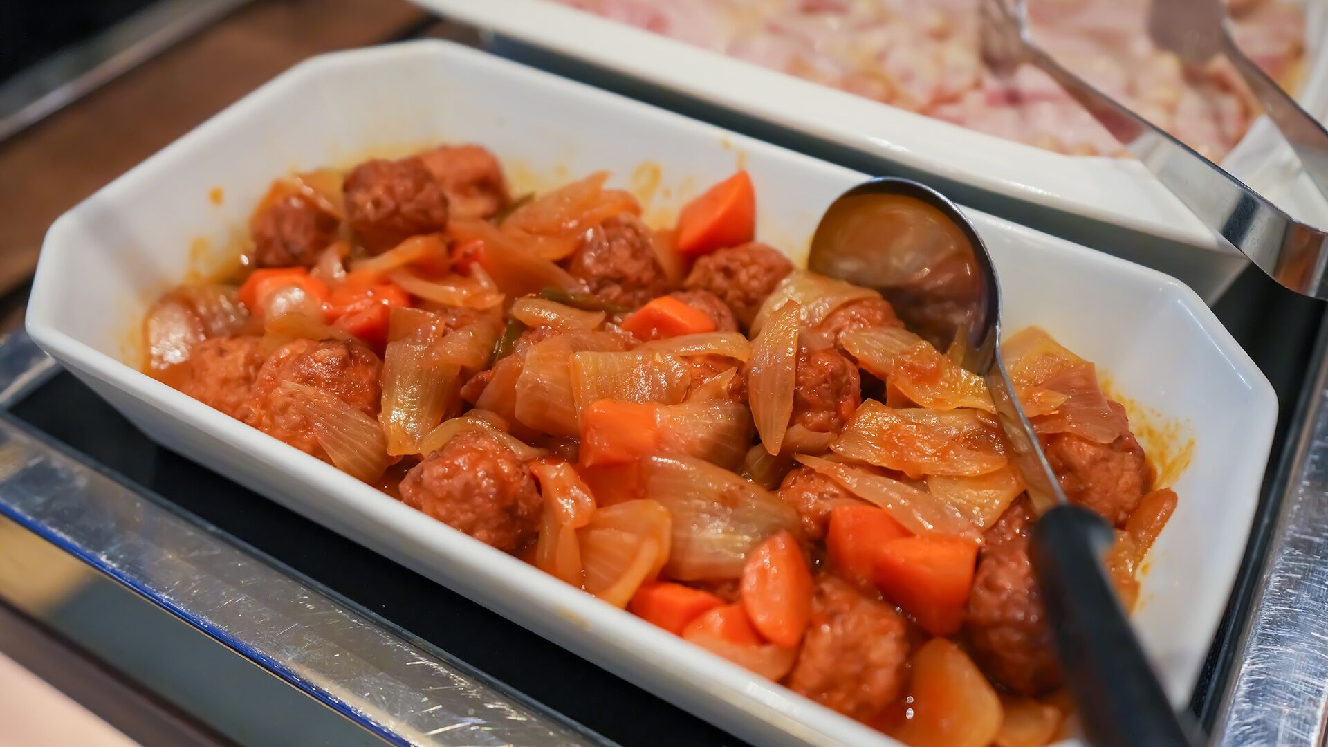 A dish of meatballs with vegetables in a white dish.