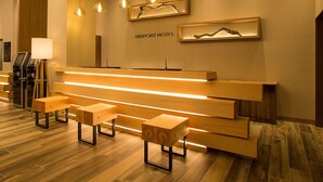 A reception desk with a wooden finish, multiple seating options, and overhead lighting. - Airport Hotel Kumamoto (Ozu)
