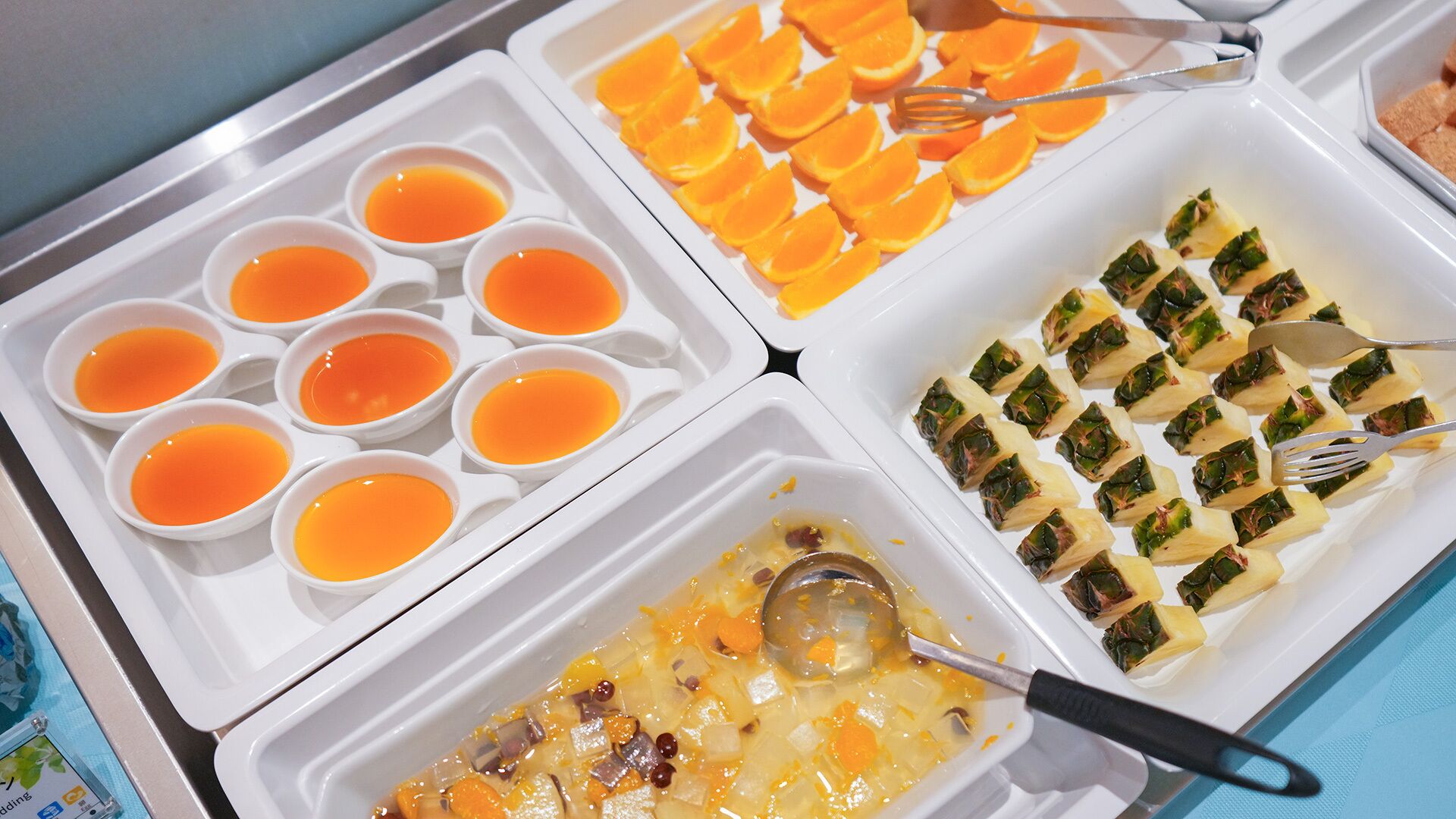 Un buffet proposant une variété de plats, notamment des œufs, des tranches d’orange, des légumes farcis et un gratin de légumes.