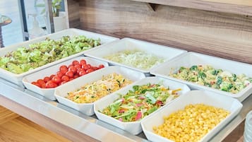 Un bufé con diversas opciones de comida, entre ellas ensaladas, verduras y cereales.