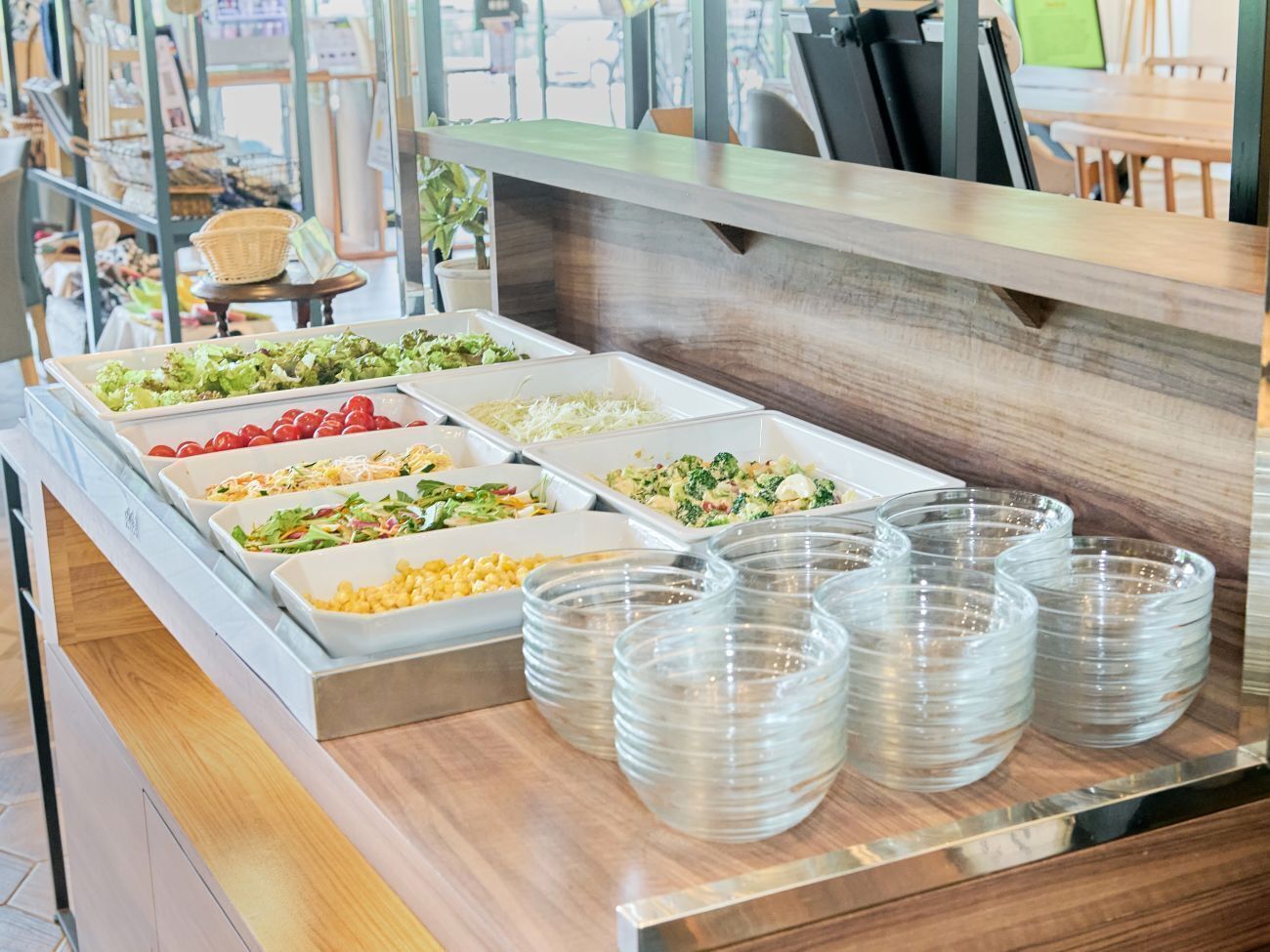 A buffet with various food options and clear plastic plates.