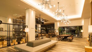 A modern hotel lobby with a central seating area, a dining space, and a restaurant. - Airport Hotel Kumamoto (Ozu)