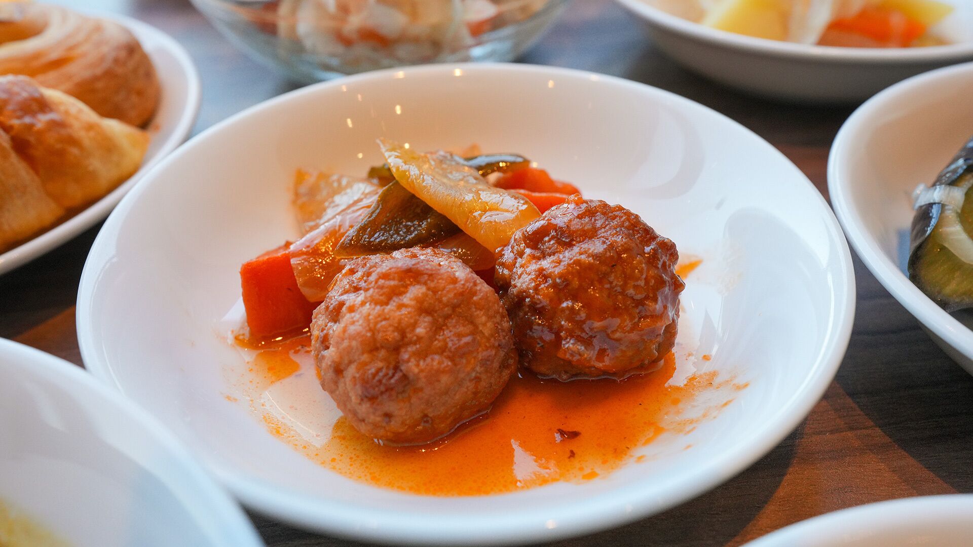 Un plato con albóndigas y verduras en salsa.