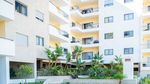 Un edificio residencial de varios pisos con balcones, un patio central con plantas y un suelo de baldosas.