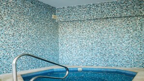 Una piscina con un muro de azulejos y una escalera de metal.