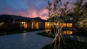 A modern house with a well-lit entrance, a paved driveway, and a garden area.