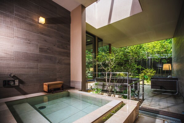 A modern indoor pool area with a glass enclosure, wooden benches, and a view of lush greenery outside. - Unzen Kyushu Hotel - Mt Resort (Unzen)
