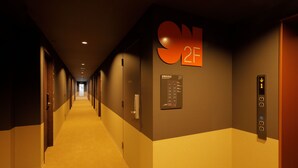 Corridoio di un albergo con indicazione della camera 2F, un ascensore e una mappa delle uscite di sicurezza.