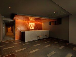 Ein moderner Empfangsbereich mit einem 'Smart Place Inn' Schild, einer Holzboden-Decke und einem gefliesten Boden.