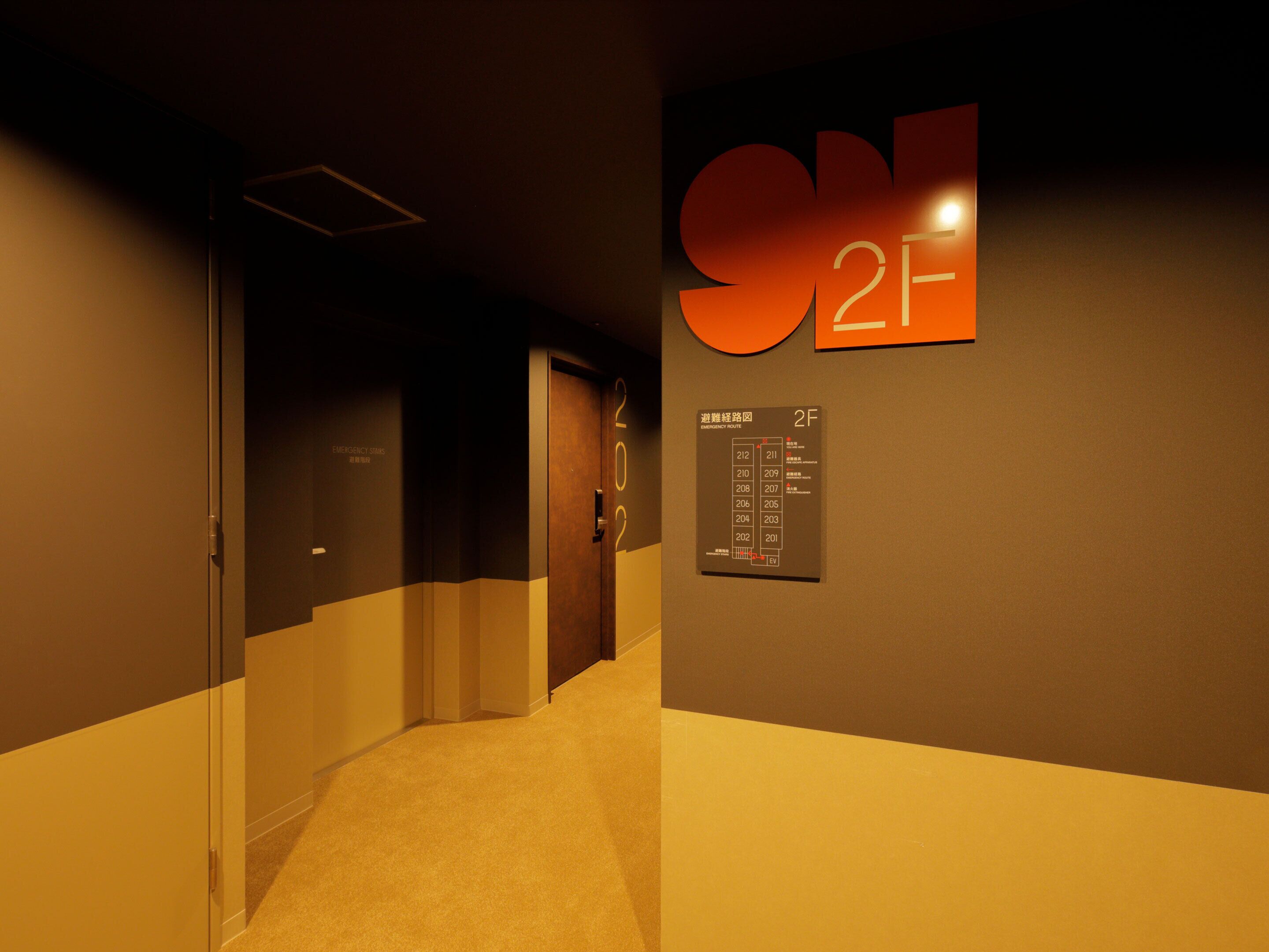 A hallway with a sign indicating room 2F and an emergency exit route.