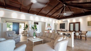 A spacious living area with a high ceiling and wooden beams, a dining area with a kitchen, and a view of the outdoors. - Direct Beachfront 6 BDR/en-suite /maid included. Excellent service. Rare gem (A) (Guana Bay Beach)