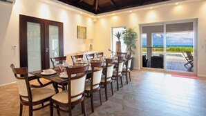 A dining area with a long table, multiple chairs, and a view of the outdoors. - Direct Beachfront 6 BDR/en-suite /maid included. Excellent service. Rare gem (A) (Guana Bay Beach)