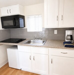 A compact kitchen with a microwave, stove, sink, and white cabinets. - Walkable Roosevelt Row / 1BR 1BA Downtown Stay (Phoenix)