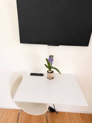 A white table with a remote control and a potted plant.