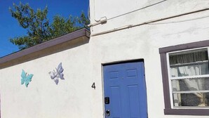 A white building with a blue door, a window, and a butterfly decoration. - Walkable Roosevelt Row / 1BR 1BA Downtown Stay (Phoenix)