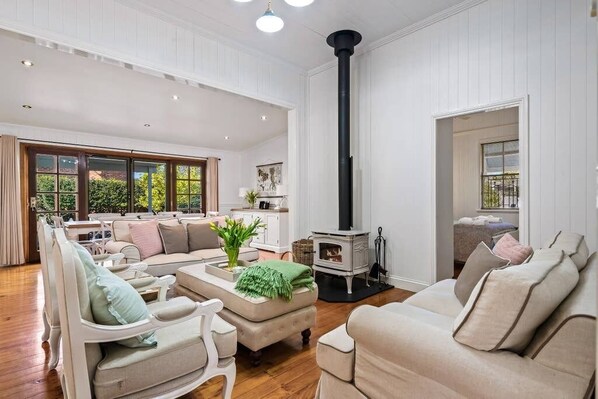 A spacious living room with a high ceiling, a large window, and a built-in wood-burning stove.