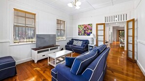Een woonkamer met een televisie, banken en een schilderij.