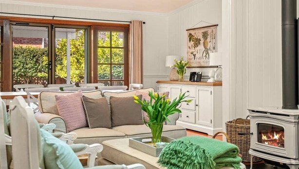 Een gezellige woonkamer met een bank, een open haard en een raam met gordijnen.