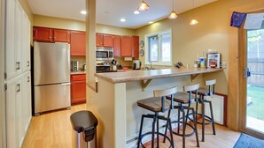 A kitchen with a central island, bar stools, a refrigerator, microwave, and a window overlooking a backyard. - 2 Mi to Frisco Ski Hill: Mountain Home w/ Hot Tub! (Frisco)