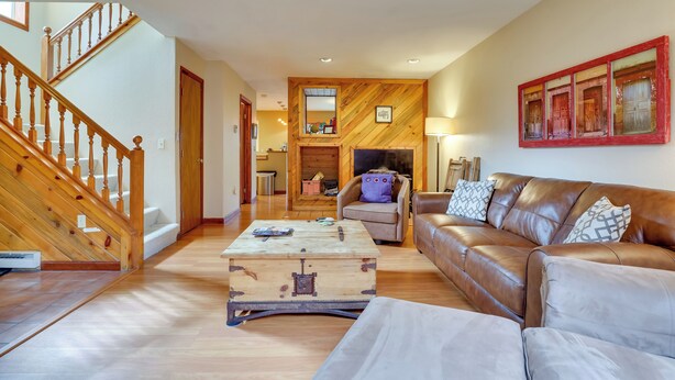 A spacious living room with a wooden staircase, a leather sofa, and a wooden coffee table. - 2 Mi to Frisco Ski Hill: Mountain Home w/ Hot Tub! (Frisco)