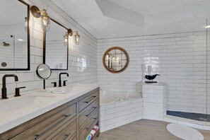 A modern bathroom with a vanity, a bathtub, and a round mirror.