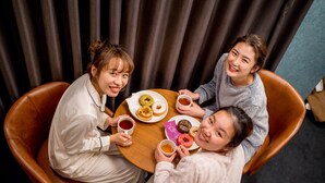 Three people seated at a round table with plates of food and cups of tea, in a room with dark curtains and a visible floor. - RESI STAY BRiX (Kyoto)