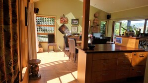 A kitchen with a wooden countertop, a dining area with chairs, and a view of the outdoors through a window.