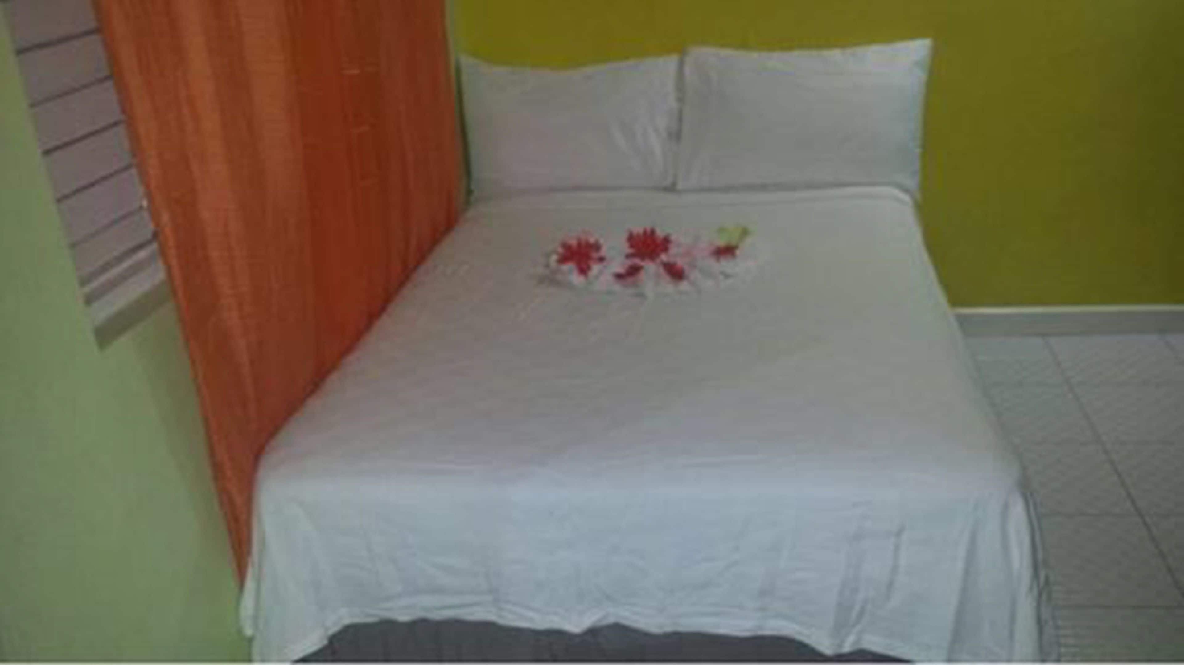 Una cama con una colcha blanca y una almohada estampada con flores.