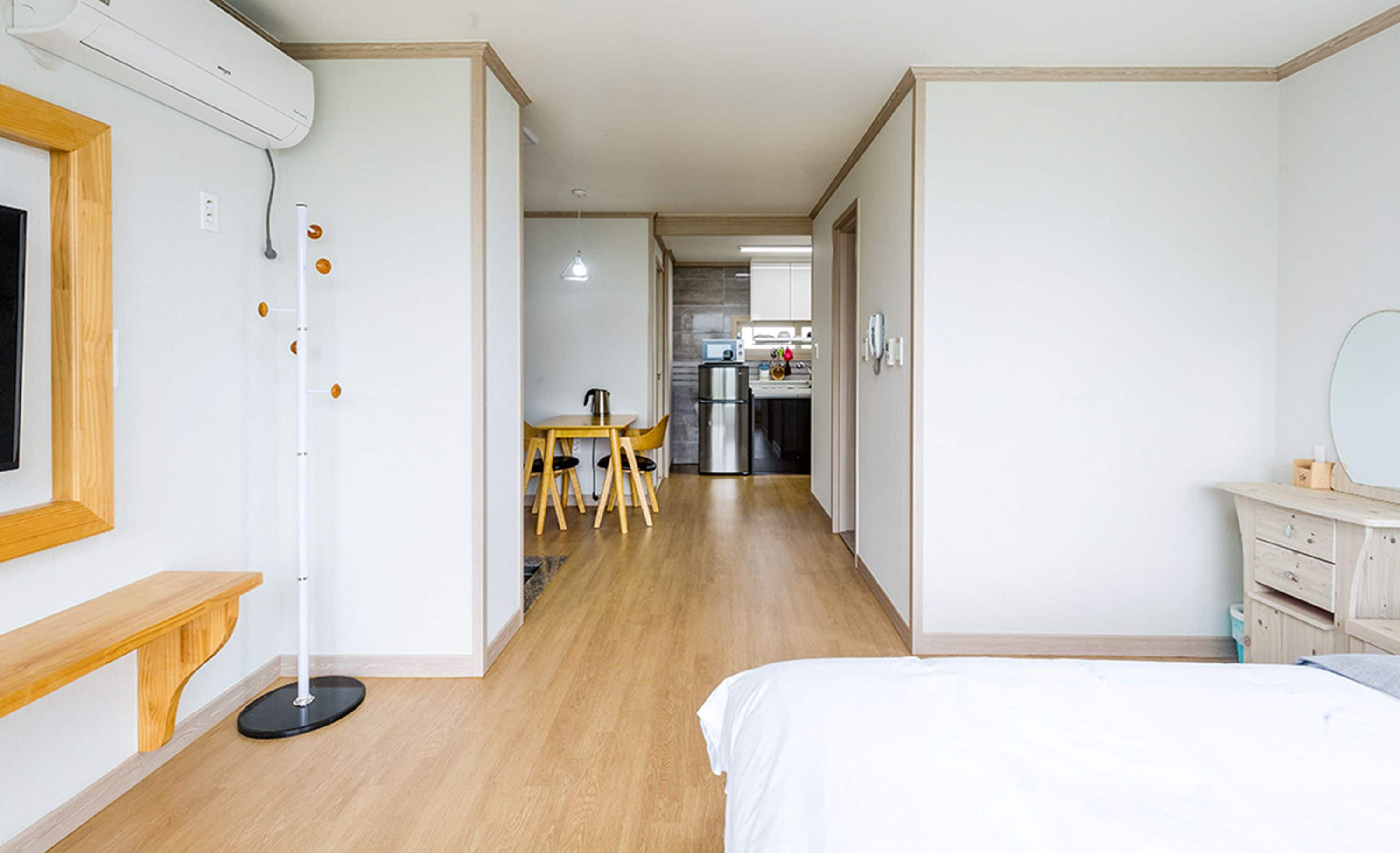 Hotellihuoneessa on sänky, työpöytä ja tuoli. Taustalla näkyy pieni keittiönurkkaus.