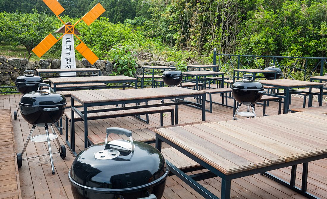 Un espace extérieur aménagé pour les repas, avec plusieurs tables et des barbecues.