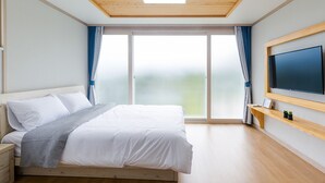 Un dormitorio moderno con una cama grande, un televisor y una puerta corrediza de vidrio que da a un balcón.