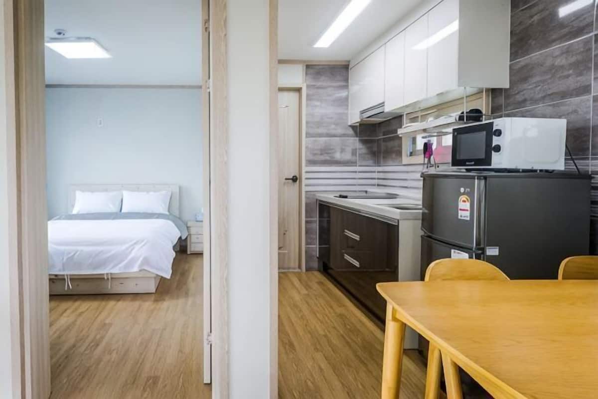 A compact room with a bed, a kitchenette, and a dining area.