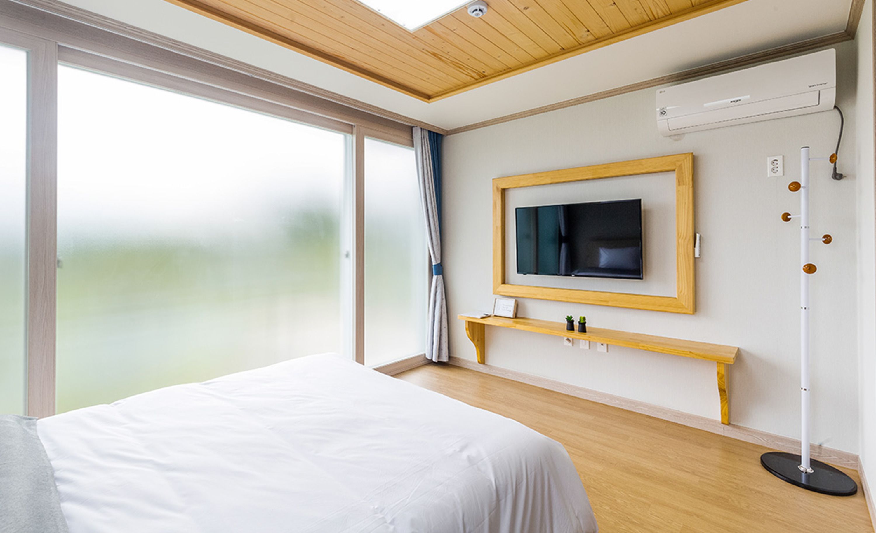 Une chambre d’hôtel moderne avec un grand lit, un téléviseur fixé au mur, une table de chevet et une lampe sur pied.
