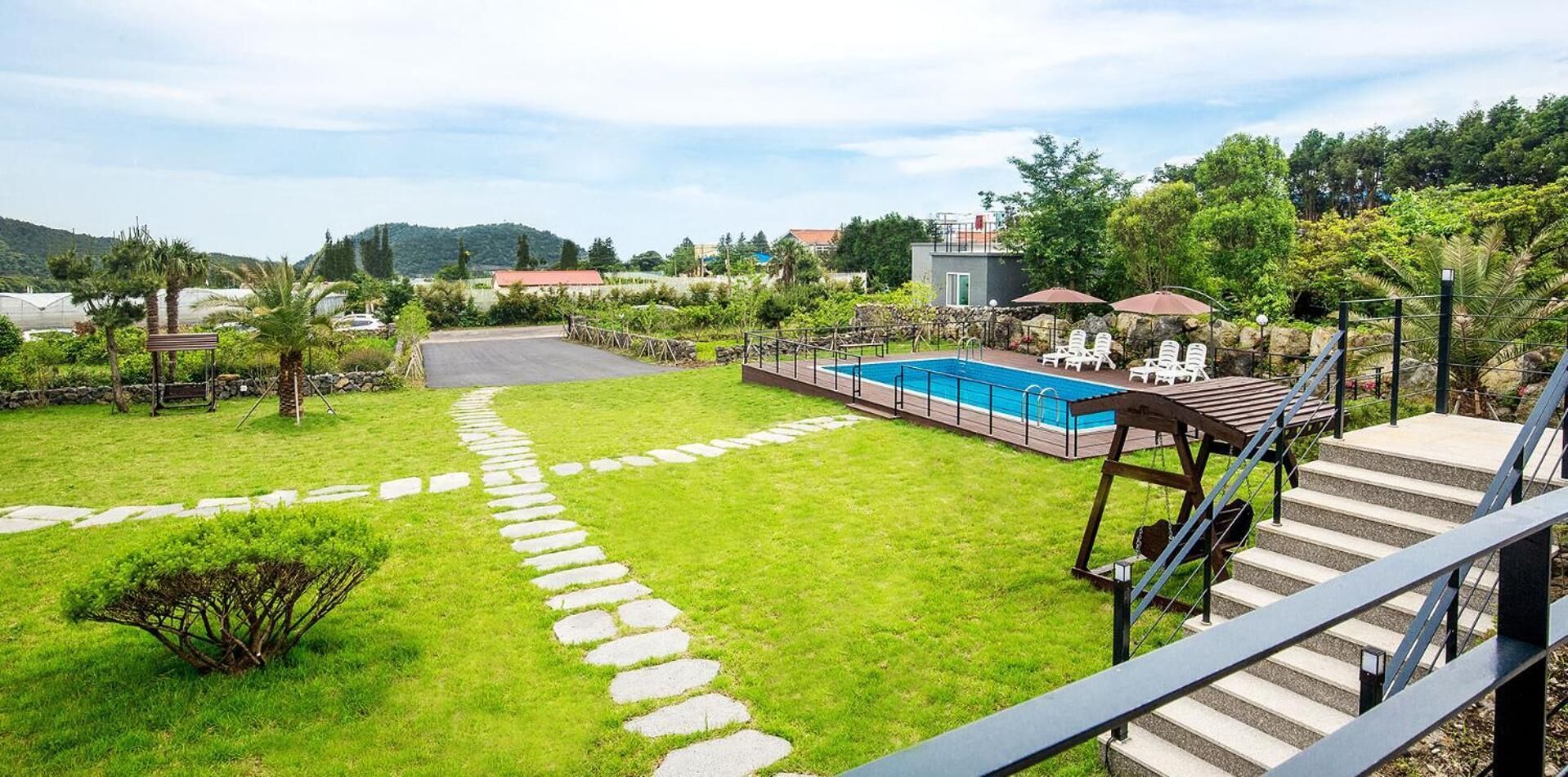 A backyard with a swimming pool, stone pathway, and outdoor seating area.