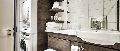 A modern bathroom with a built-in washing machine, a sink with a mirror, and wooden cabinetry.