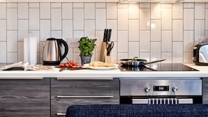 A modern kitchen with a white tiled backsplash, stainless steel appliances, and a variety of kitchen utensils.