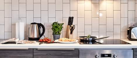 A modern kitchen with a white tiled backsplash, stainless steel appliances, and a variety of kitchen utensils.