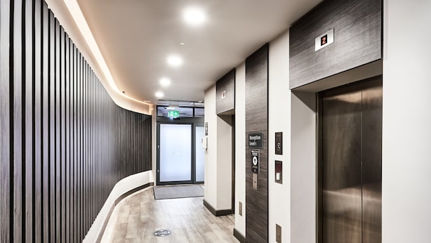 A modern hallway with a wooden slat wall, a reception desk, and an elevator. - Citadines City Centre Liverpool (Liverpool)