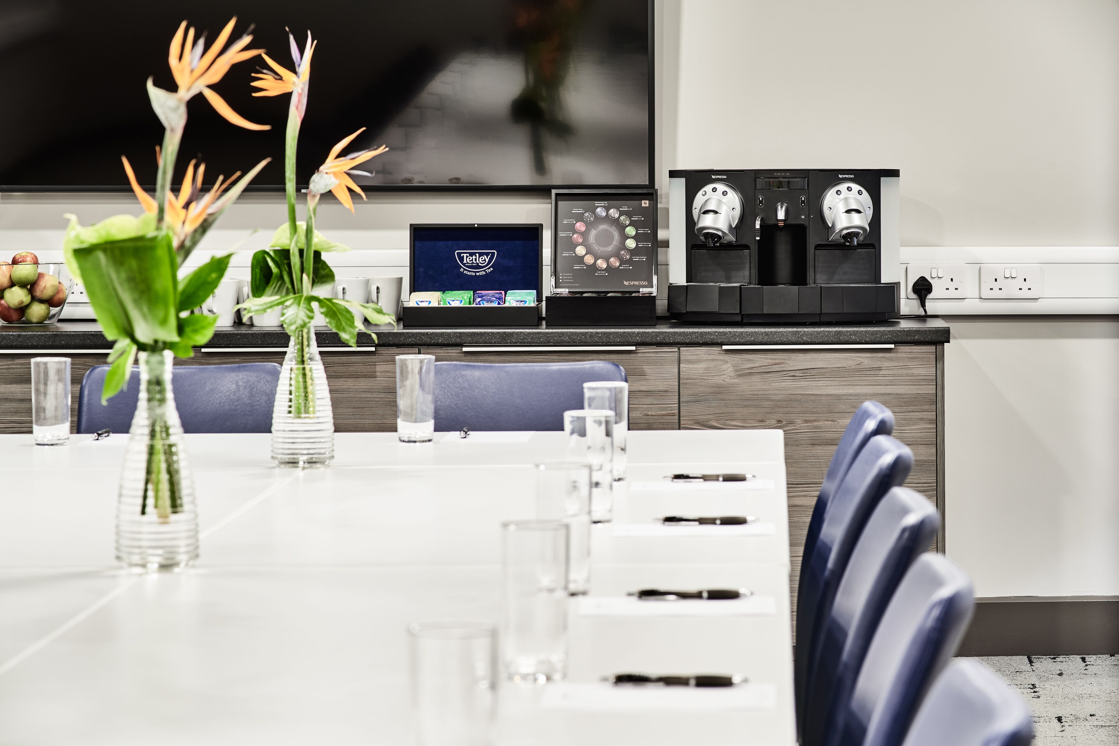 A modern kitchen with a coffee machine, a Nespresso machine, and a display of Tetley tea boxes.