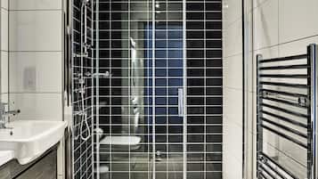 A modern bathroom with a glass-enclosed shower, a white sink, and a towel rack.