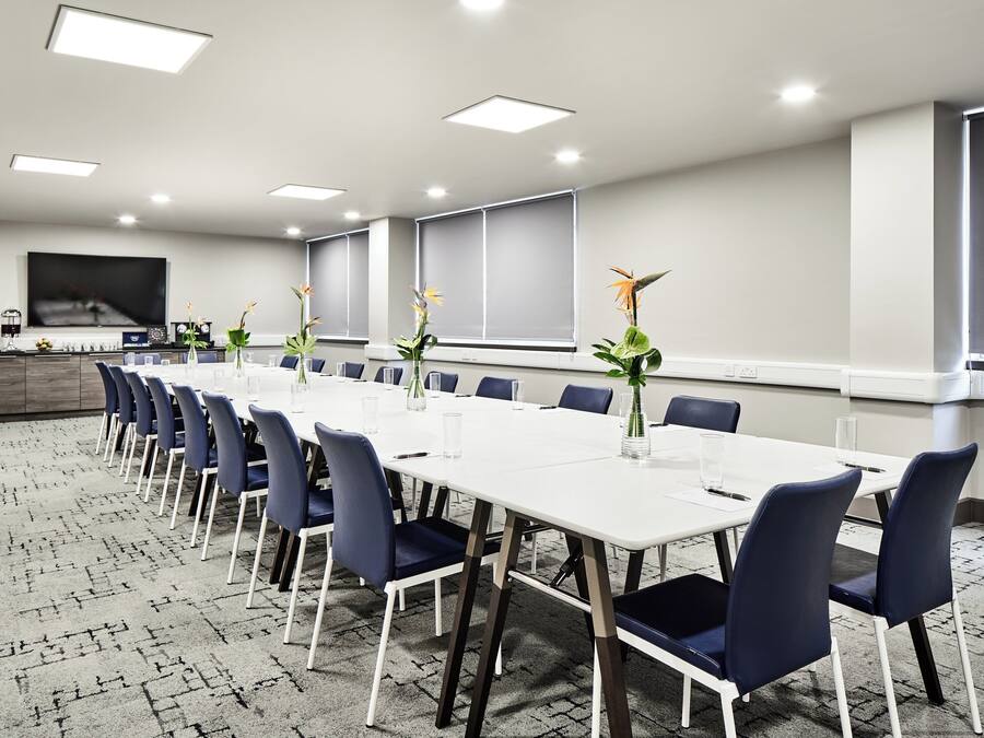 A conference room with a long table, chairs, and a TV screen.